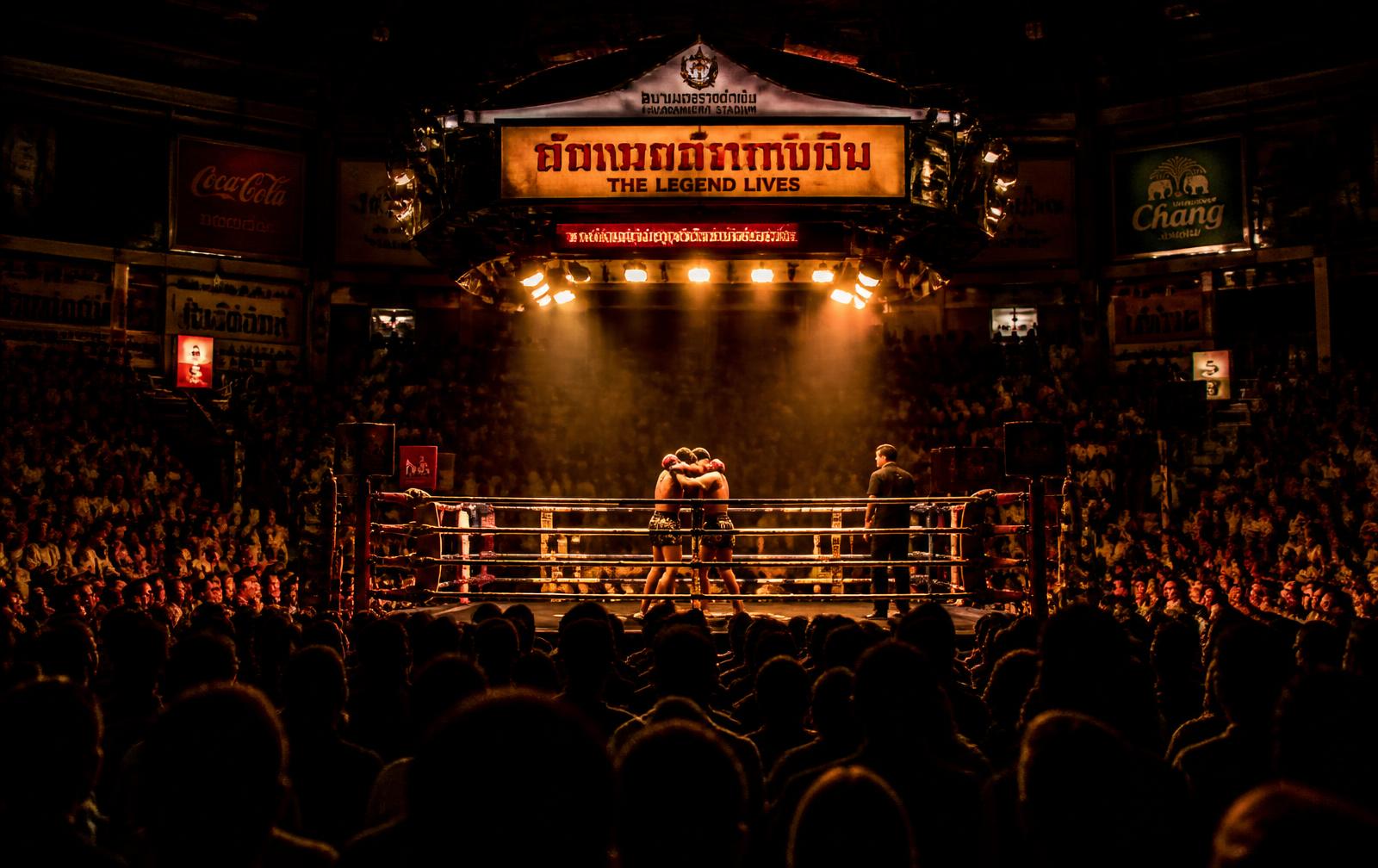 Fighters in the ring under stadium lights at Rajadamnern Stadium in Bangkok